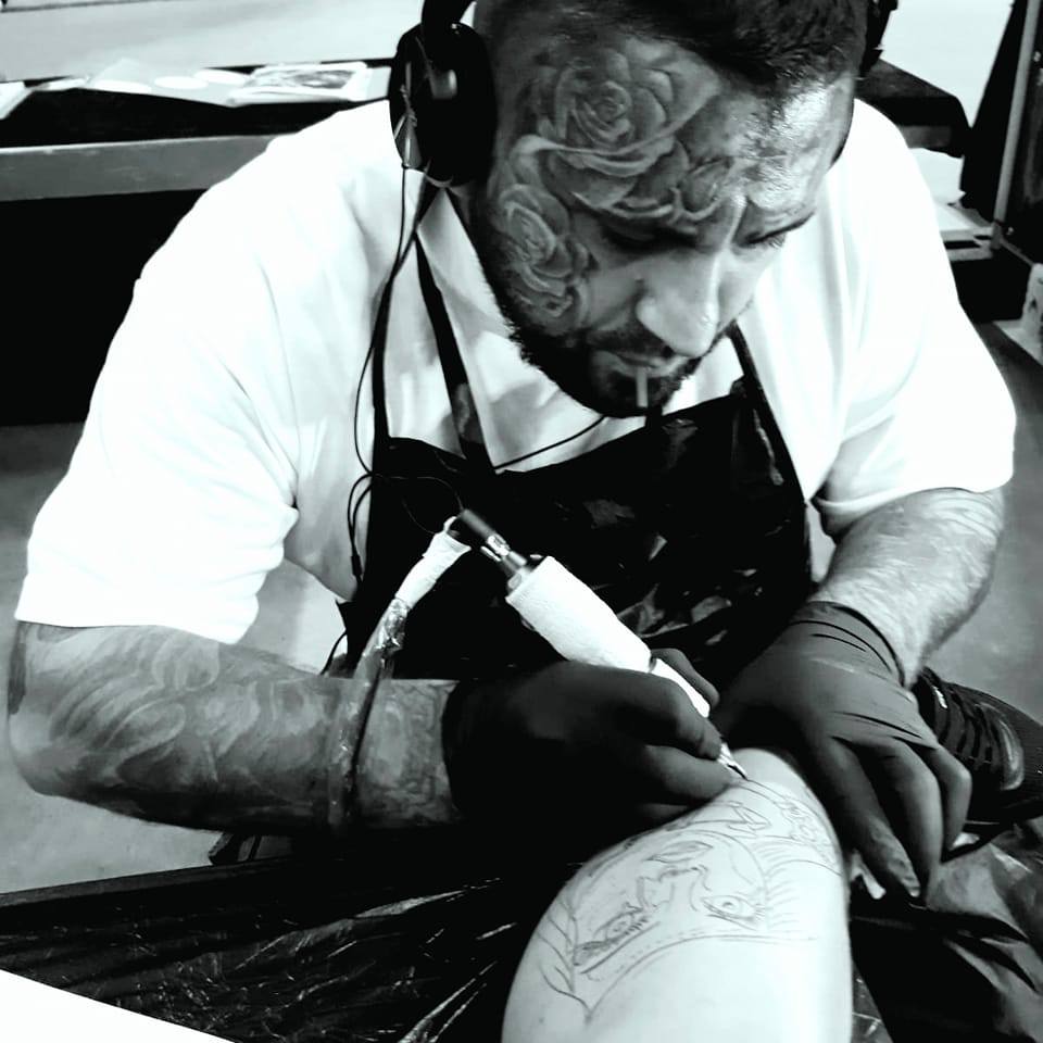 Robert Grieger bei der Arbeit an einem Tattoo, Schwarzweißfoto