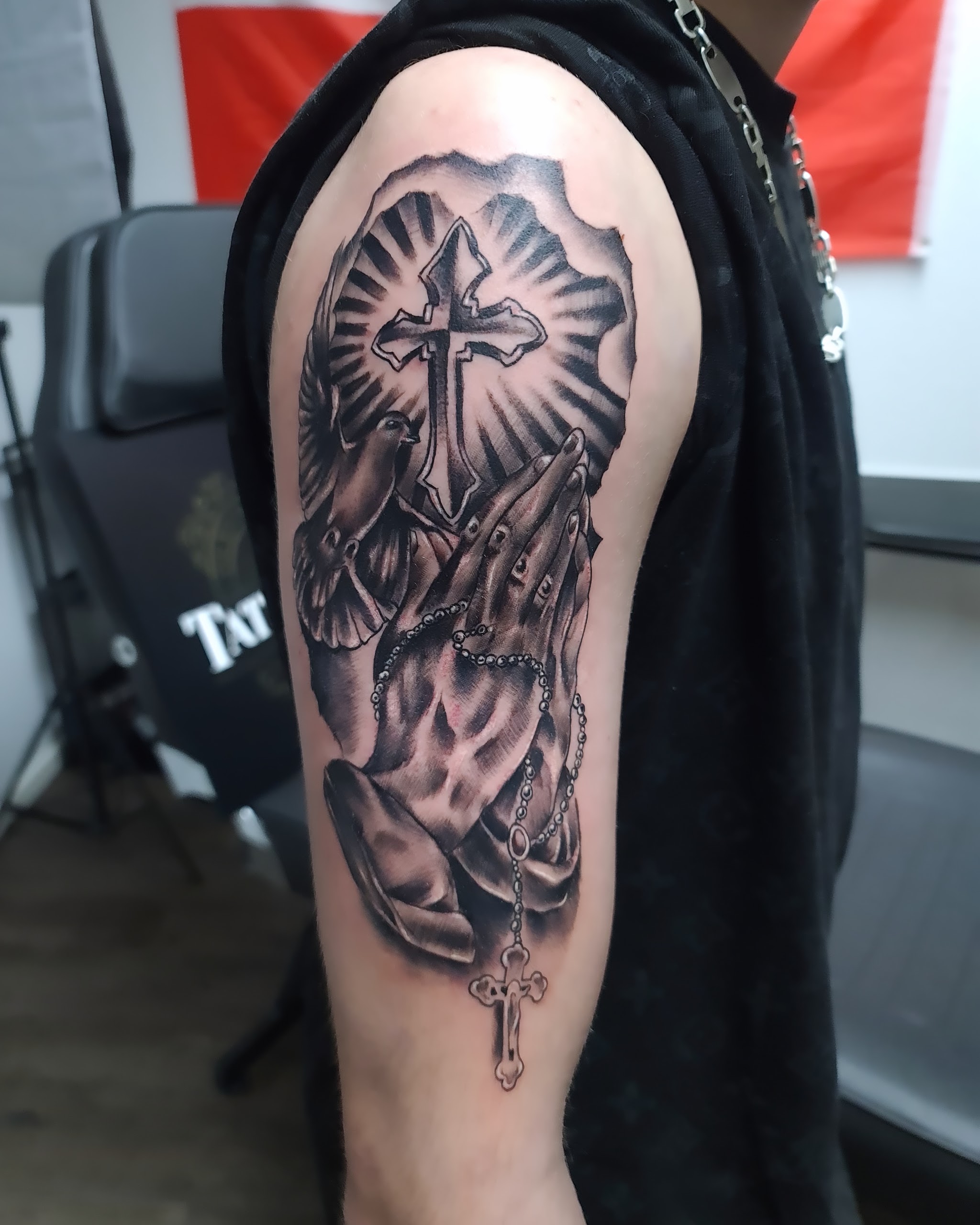 Black-&-Grey-Tattoo am Oberarm: betende Hände mit Kreuz und Rosenkranz