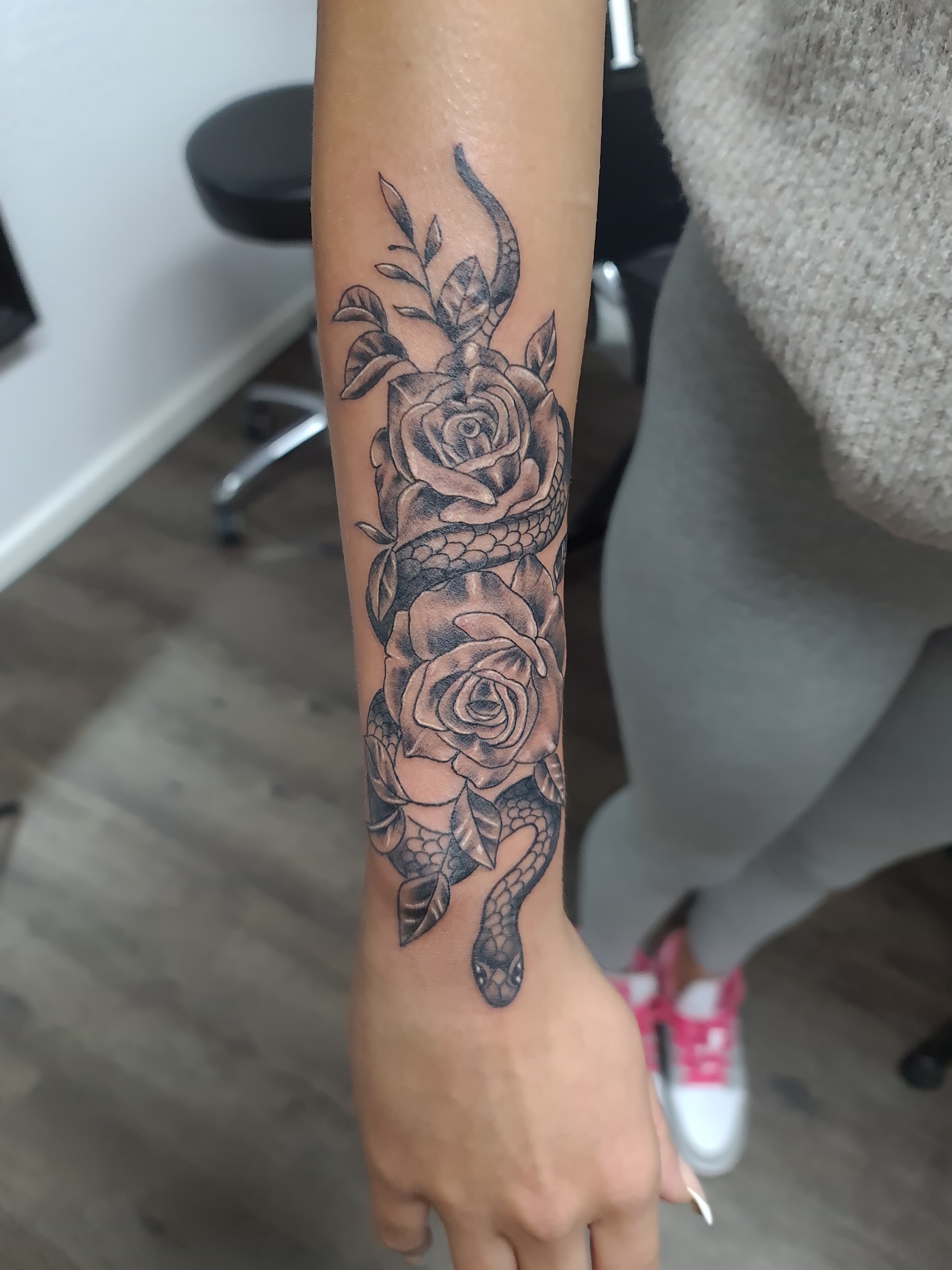 Unterarm-Tattoo: Rosen, um die sich eine Schlange windet